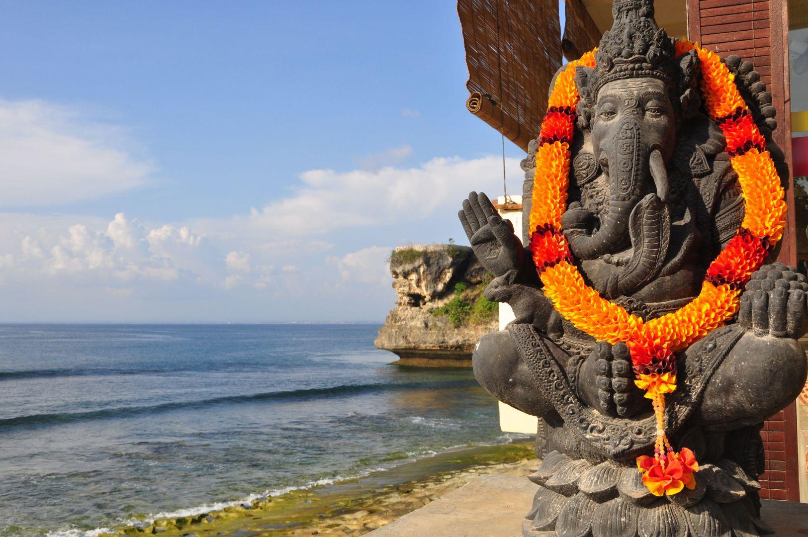 Vir&aacute;gf&uuml;z&eacute;rrel d&iacute;sz&iacute;tett Ganesha szobor tr&oacute;pusi tengerparton Indon&eacute;zi&aacute;ban