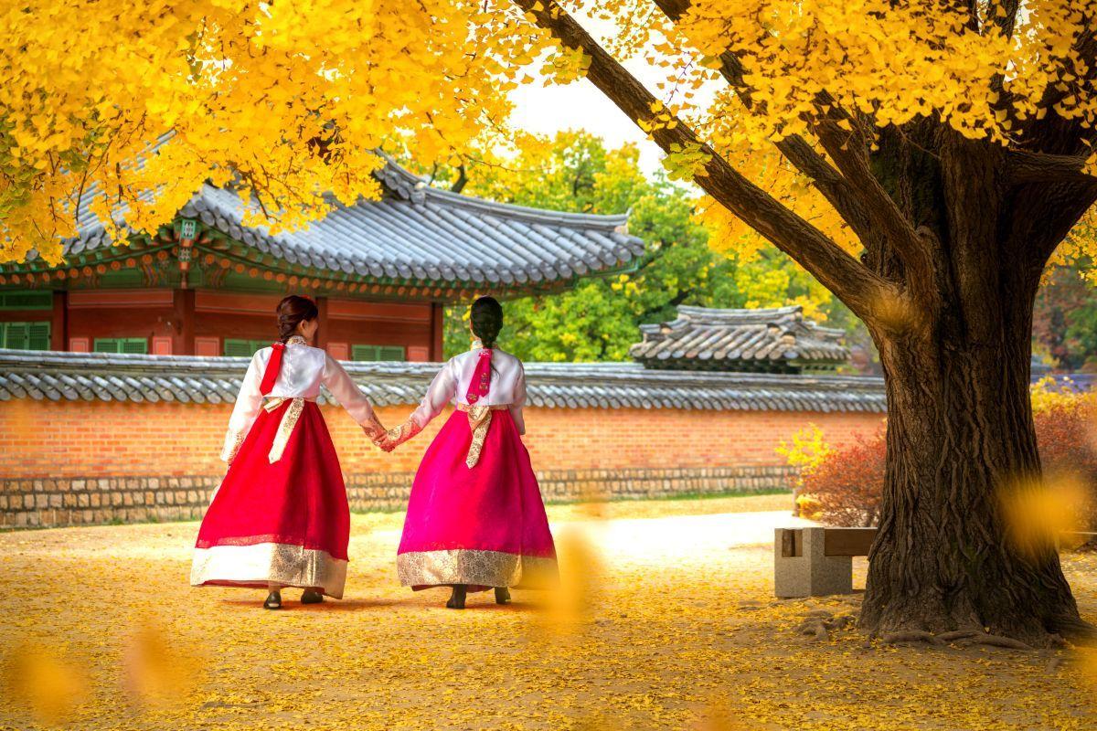 Hagyom&aacute;nyos hanbok ruh&aacute;t viselő nők egy sz&ouml;uli palot&aacute;n&aacute;l ősszel